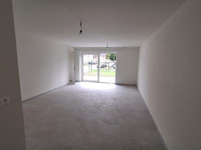 Woonkamer met witte muren, grijze tegelvloer en één groot schuifraam dat zorgt voor natuurlijk licht