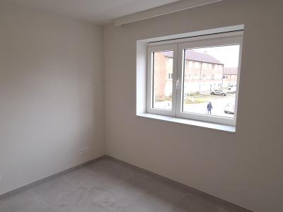 Slaapkamer met één raam, witte muren en grijze vloer